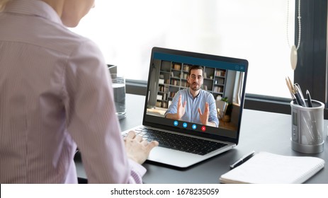 During corona virus or covid19 pandemic outbreak all negotiations performing via videoconferencing application, process of job interview distantly, view over female shoulder applicant at laptop screen - Shutterstock ID 1678235059