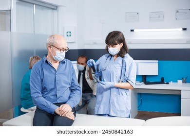 During coronavirus epidemic, nurse practitioner grasps CT scan data during medical consultation with elderly man. Healthcare professional describes radiography diagnostic and lung therapy. - Powered by Shutterstock