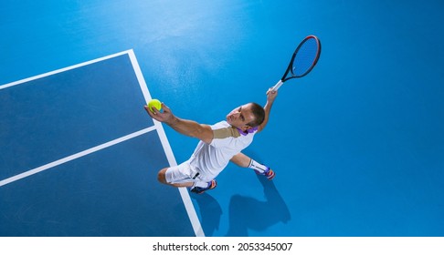 During game. Concentration. Portrait of male professional tennis player serving a ball, training over gym background. Concept of active life, team game, energy, sport, competition. Copy space for ad. - Powered by Shutterstock