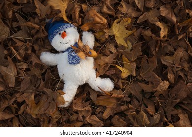 During The Golden Hour Of The Day, A Snowman Has Fun Playing In The Autumn Leaves, Making Snow Angels, Throwing Leaves In The Air And Escaping The Chill Of Winter. Horizontal, Flat Layout, Copy Space.