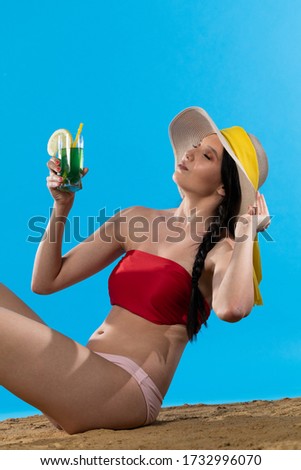 During hot summer, the teenager with a hat on her head holds an alcoholic drink in her hand.