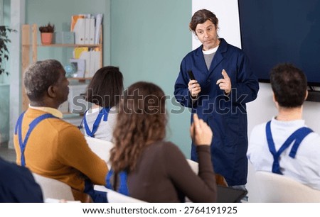 During lesson, middle- age man worker teacher tells material and gives lecture, speaks to group of students. Introductory lecture for new staff employees and theoretical introduction to profession