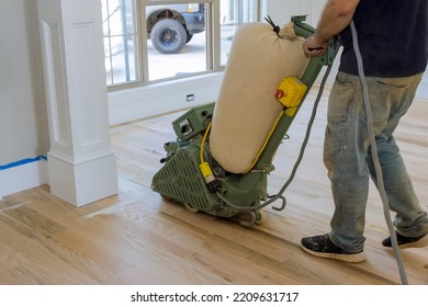 During Of Newly Constructed House, Floor Sander Is Being Used To Grind Down A Wooden Parquet Floor