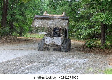 During The Reconstruction Of An Old Road, A Transports Bobcat Tractor Is Moving And Unloading Gravel