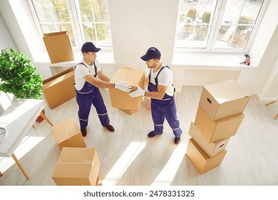 During relocation or delivery, two movers are seen carrying boxes into either a home or office space. Coordinated efforts reflect the professionalism of a relocation service. - Powered by Shutterstock