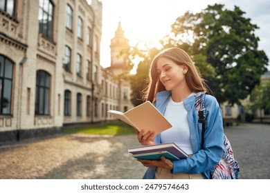 During sunset, a college student takes pleasure in reading a book outdoors near the university building, blending into the serene campus atmosphere with a backpack on her shoulders - Powered by Shutterstock