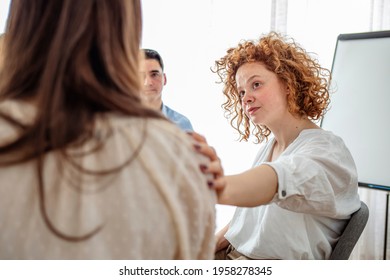 During a support group session a mid adult woman comforts her friend. Her hand is on the woman's shoulder. Therapy session concept encourage support patients in addiction talk share problem  - Powered by Shutterstock