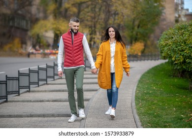 During the walk. Nice happy couple holding their hands together while walking along the street