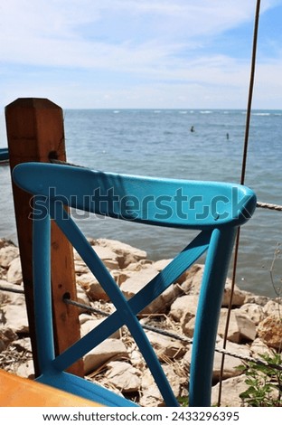 Durres, Albania - September, 3rd, 2022: Spectacular view to the Adriatic sea from 2 the Kitarrat Arome Deti restaurant. Beautiful wooden retro chair hand painted turquoise.   Hot summer day.