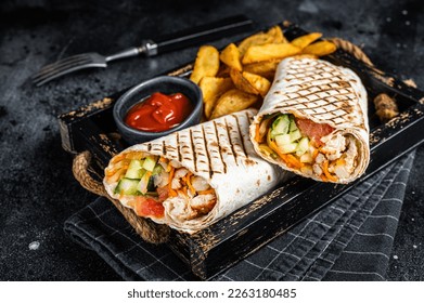 Durum doner kebab or Shawarma with meat, vegetable salad and french fries. Black background. Top view. - Powered by Shutterstock