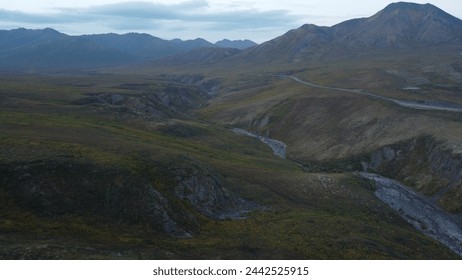 As dusk falls, an aerial drone captures the rugged patterns of a mountain valley and meandering river in the wilderness of Yukon. - Powered by Shutterstock