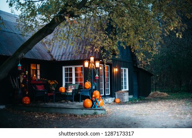 At Dusk Outside On Halloween Night, Lit Jack-o-lanterns Decorate The Porch Of A Country Farm.