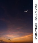 Dusk sky vertical after sundown with crescent moon over orange sunlight and dark blue sky on twilight well space for text Ramadan, Eid al Adha, Eid al Fitr