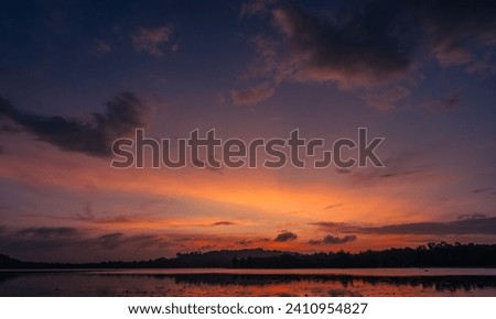 Dusk, Sunset sky clouds in the evening on twilight after sundown over silhouette mountain and lake water reflection with orange sunlight in Golden hour, Horizon sky landscape background  