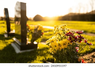 Dusk at a winter's English cemetery seen with in-focus flowers in a burial plot.
