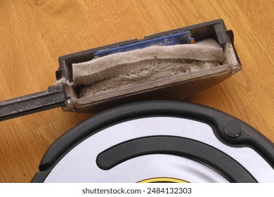 A dust bin full of dust near a robot vacuum cleaner. Close up. - Powered by Shutterstock