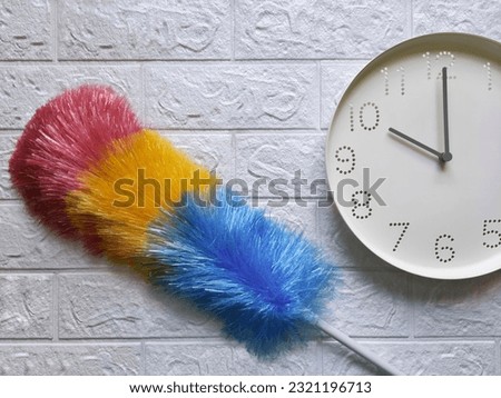 Dust brush and watch. 10 o'clock, morning. Quick cleaning with pipidastra. Housewife cleaning, household to-do list, timetable and schedule housework concept. Duster cleaning on brick wall.