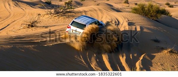 Dust sand cloud splash turn car wheel. Safari\
rally drive off road car 4x4 adventure driving in the desert sand\
dune landscape.
