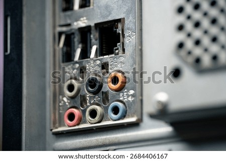 Dusty old computer back panel with audio jacks, USB ports and Ethernet connector, close up of vintage PC hardware
