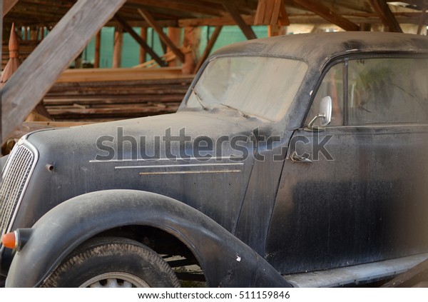 Dusty old veteran car\
parked in the barn