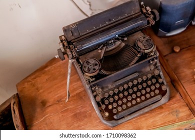 a dusty and rustic black antique typewriter on the brown wooden table. vintage thing suitable for postcard, poster, graphic resources. retro scene