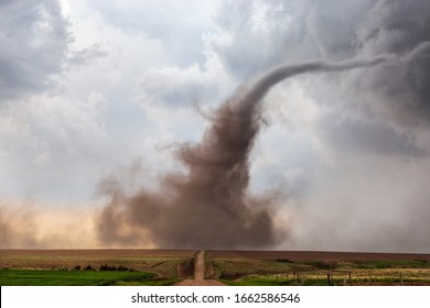 A Dusty Tornado Spins Beneath A Supercell Thunderstorm Over A Field.