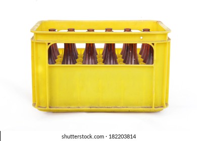 Dusty vintage yellow beer crate with empty brown beer bottles on white background
