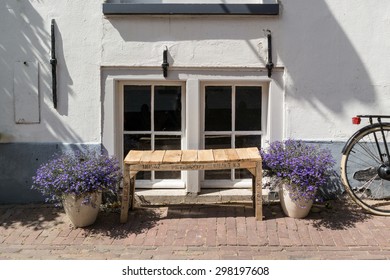 Dutch city street scene with selfmade wooden bench, flowers in pots and wheel of bicycle in front of windows of old house in Amersfoort in province of Utrecht, Netherlands - Powered by Shutterstock