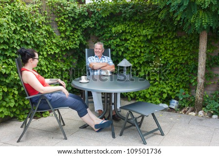 Dutch Daughter and Father sitting at a garden set in the back yard chatting and drinking a hot beverage
