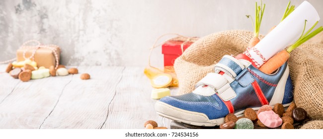 Dutch holiday Sinterklaas composition with childrens shoe with carrots for Santa's horse and sweets with copy space. Banner. - Powered by Shutterstock