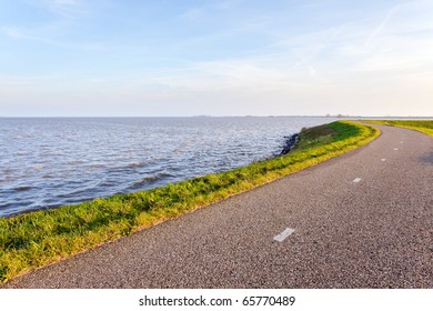 Dutch landscape with dike and road under blue sky