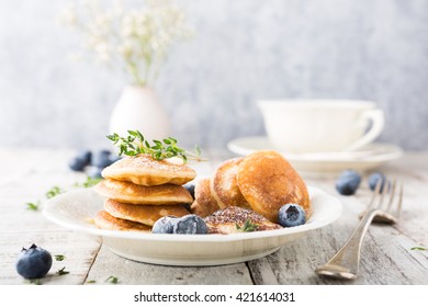 Dutch mini pancakes called poffertjes with blueberries and thyme, sprinkled with powdered sugar. Healthy food concept with copy space.