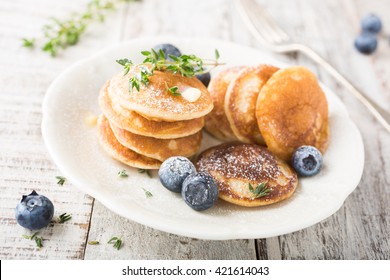 Dutch mini pancakes called poffertjes with blueberries and thyme, sprinkled with powdered sugar. Healthy food concept.