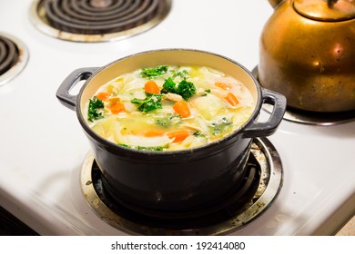 Dutch Oven On A Stove While Cooking Chicken Noodle Soup.