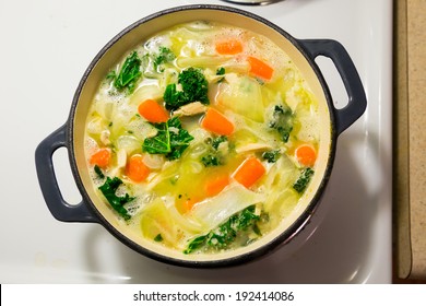 Dutch Oven On A Stove While Cooking Chicken Noodle Soup.