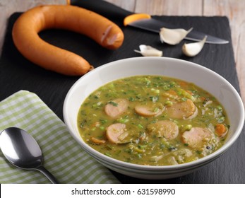 Dutch pea soup snert with smoked sausage Rookworst on a rustic table
