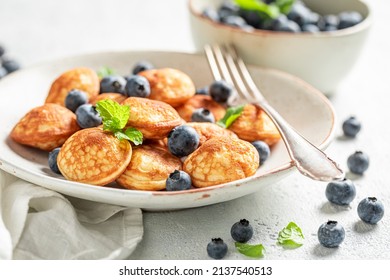 Dutch and sweet mini pancakes with sweet fruits. Poffertjes with fruits as sweet breakfast.