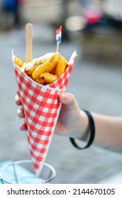 Dutch War Fries  with the Canals of Amsterdam on the background. Typical Dutch street food .Hand holding Traditional Potato Dish From Netherlands. Fried potatoes   in Paper Cone topped with Mayonnaise - Shutterstock ID 2144670105