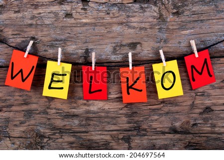 The Dutch Word Welkom, which means Welcome, on Notes Hanging on a Line on Wooden Background