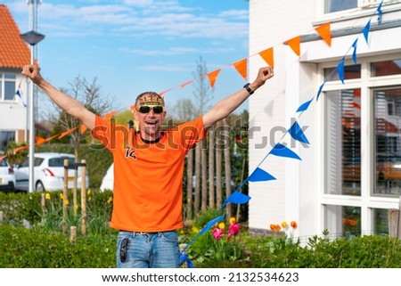 Dutchman celebrating kings day on the road during a street party dressed in orange in Holland the Netherlands. Koningsdag is a traditional festival to celebrate the Dutch royal family. Dutch bunting.
