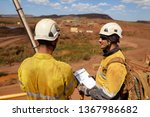 Duty of care senior businessman supervisor wearing white safety hard hat protection holding folder paperwork and conducting safety checking list on younger newest miner construction mine site Sydney 