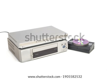 Dvd player over vhs player next to video tapes and cds isolated on white background. Image of appliances horizontally with copy space.