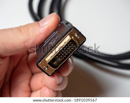 The DVI cable is black in the male hand. Cable for transmitting video images to digital display devices.