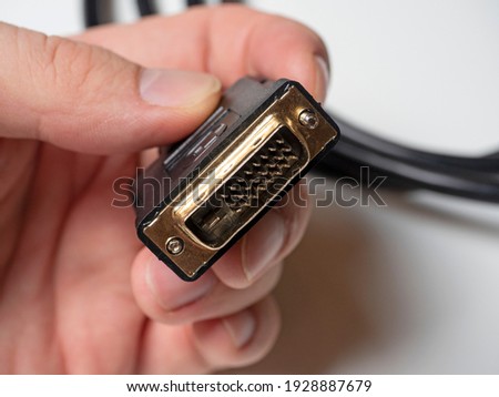 The DVI cable is black in the male hand. Cable for transmitting video images to digital display devices. Selective focus