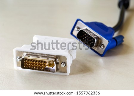 Dvi-d socket of white adapter for blue vga socket monitor cord behind it. Connection of computer devices with plugs of different types. Close-up.