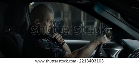 DX Daytime shot of Caucasian American police officer patrolling streets of neighborhood in patrol vehicle