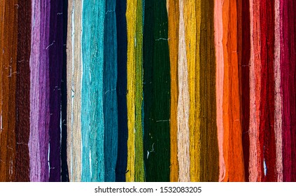 Dyed Colored Yarn Hanging On Wall In Bunches Forming A Rainbow Pattern