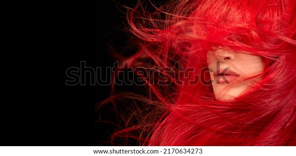 Dyed hair\
care and fashion concept. Fashion model girl with windswept long\
dyed red hair. Beautiful red haired woman with shiny long flying\
hair. Isolated on black with copy\
space
