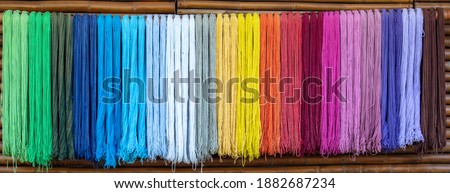 Dyed thread or cord or packthread color hang on the wall with bamboo wooden wall background.