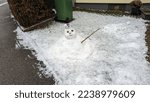 dying melting snowman on snowy garden surface next to cleared street